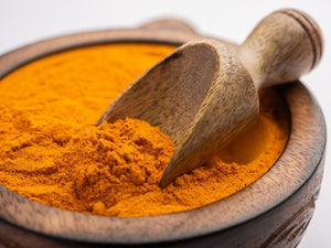 Schale voll mit Curcuma mit Holzschäufelchen