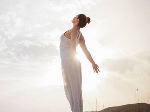 Frau in entspannter Yogapose vor Sonne